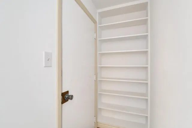 a view of a hallway with white cabinets