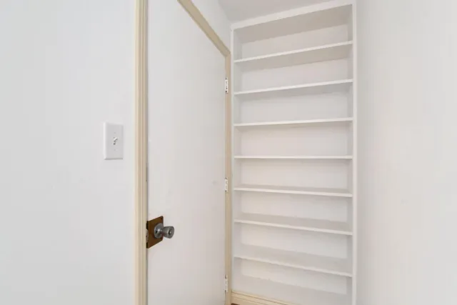 a view of a hallway with white cabinets
