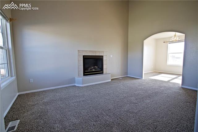 8461 Saddleman Road Peyton, CO 80831 - Photo 6 of 26 Living room features soaring ceilings, gas fireplace and archway to formal dining room.