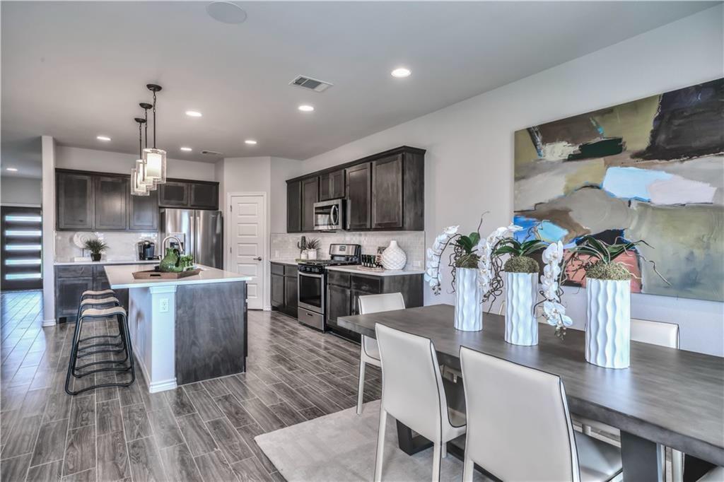 8605 Daisy Cutter Crossing Georgetown, TX 78626 - Photo 4 of 17 a kitchen with a table chairs refrigerator and microwave