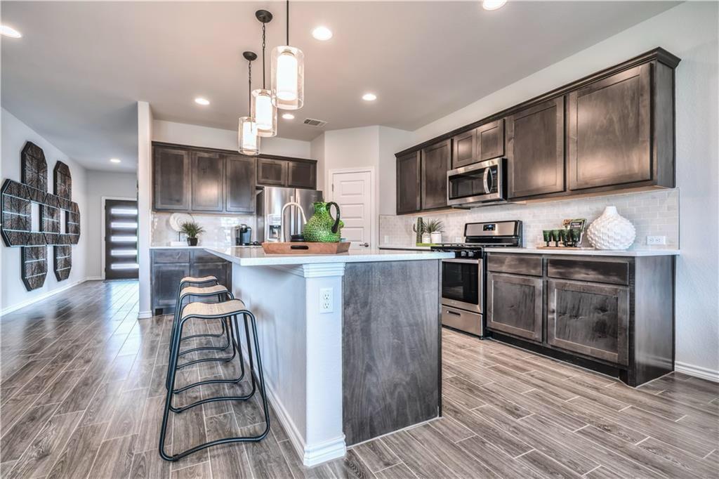 8605 Daisy Cutter Crossing Georgetown, TX 78626 - Photo 5 of 17 a kitchen with kitchen island granite countertop a stove top oven a sink a counter space and cabinets
