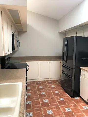 a kitchen with a refrigerator and a stove top oven