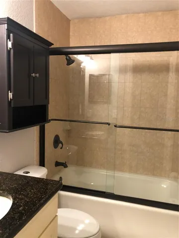 a bathroom with a granite countertop sink and a shower