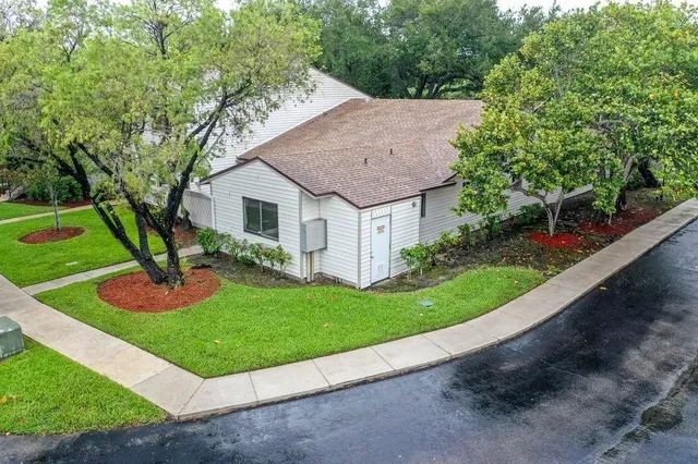 a view of a house with a yard potted plants and large tree