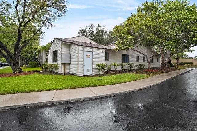 a view of a white house with a big yard and large trees
