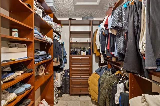 a view of walk in closet with clothes and shoes