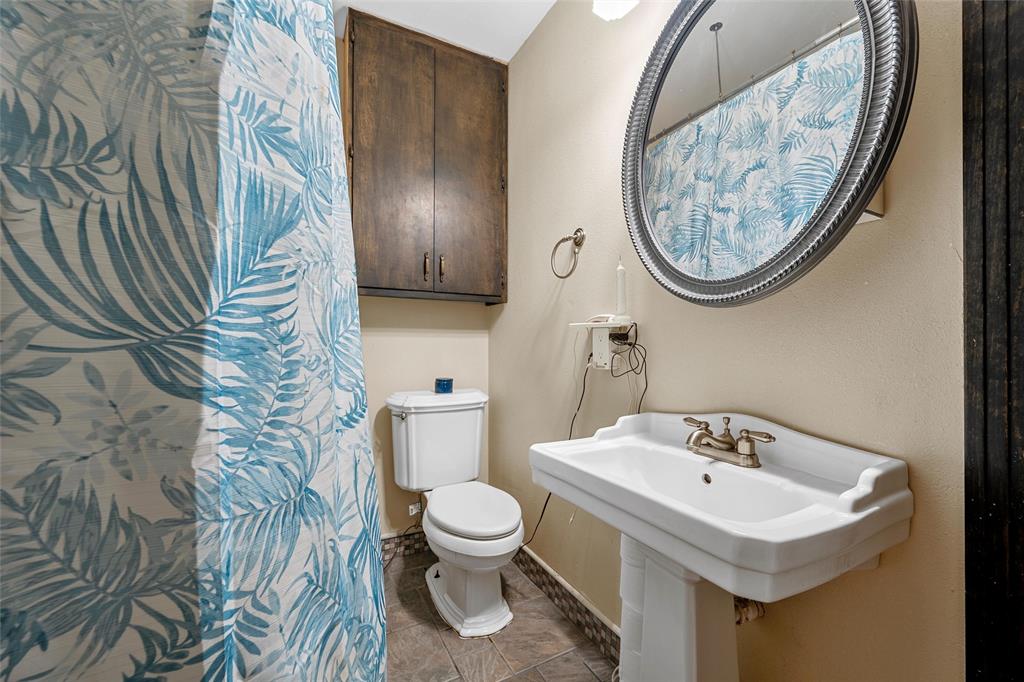 301 North 40th Street Waco, TX 76710 - Photo 20 of 26 Bathroom featuring a pedestal sink with a two-handle faucet, an oval wall mirror, and a wall-mounted wood-finish cabinet