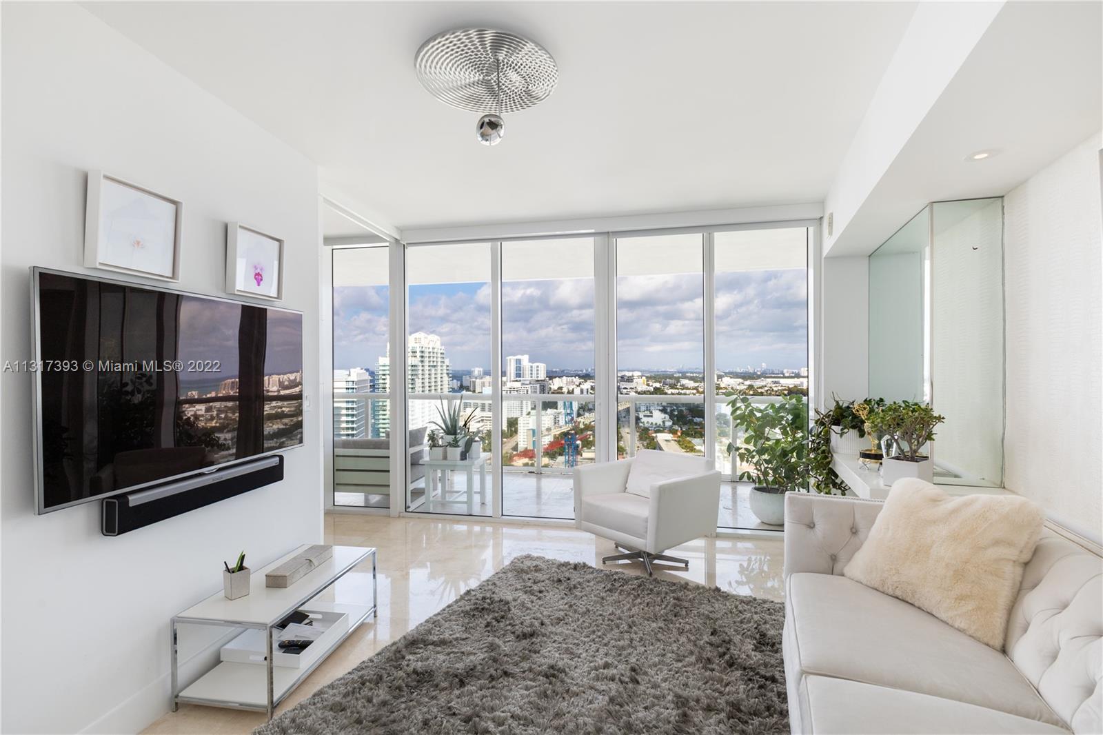 450 Alton Road, Unit 2706 Miami Beach, FL 33139 - Photo 25 of 53 a living room with furniture a flat screen tv and a floor to ceiling window