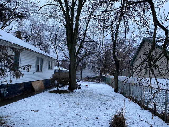 a backyard of a house with wooden bench and trees