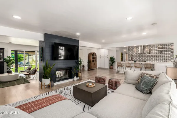 a living room with furniture a fireplace a flat screen tv and a large window