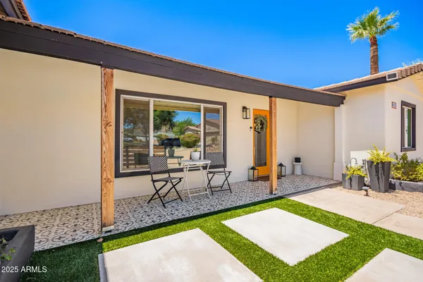 a view of a patio with table and chairs potted plants and floor to ceiling window