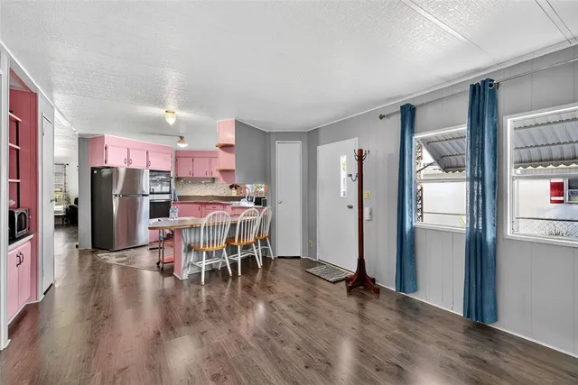 a kitchen with stainless steel appliances a dining table chairs refrigerator and sink