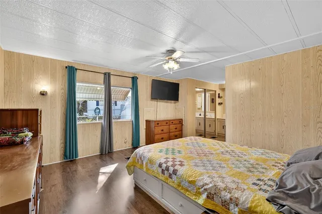 a bedroom with a large bed a flat tv screen and a dresser