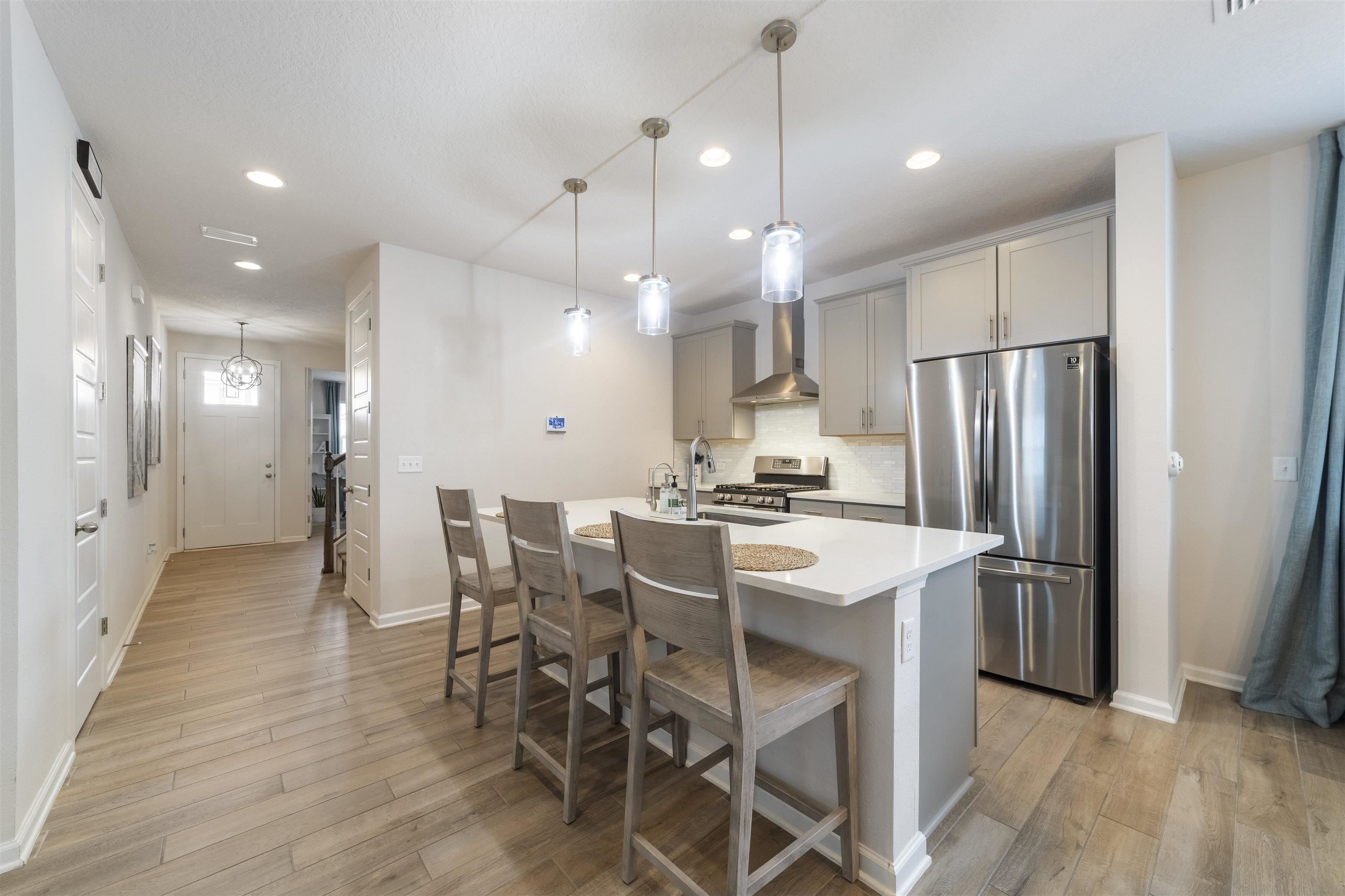 91 Pepperpike Way Street St. Augustine, FL 32092 - Photo 12 of 79 Kitchen with stainless steel appliances, gray cabinetry, a kitchen breakfast bar, pendant lighting, and a center island with sink