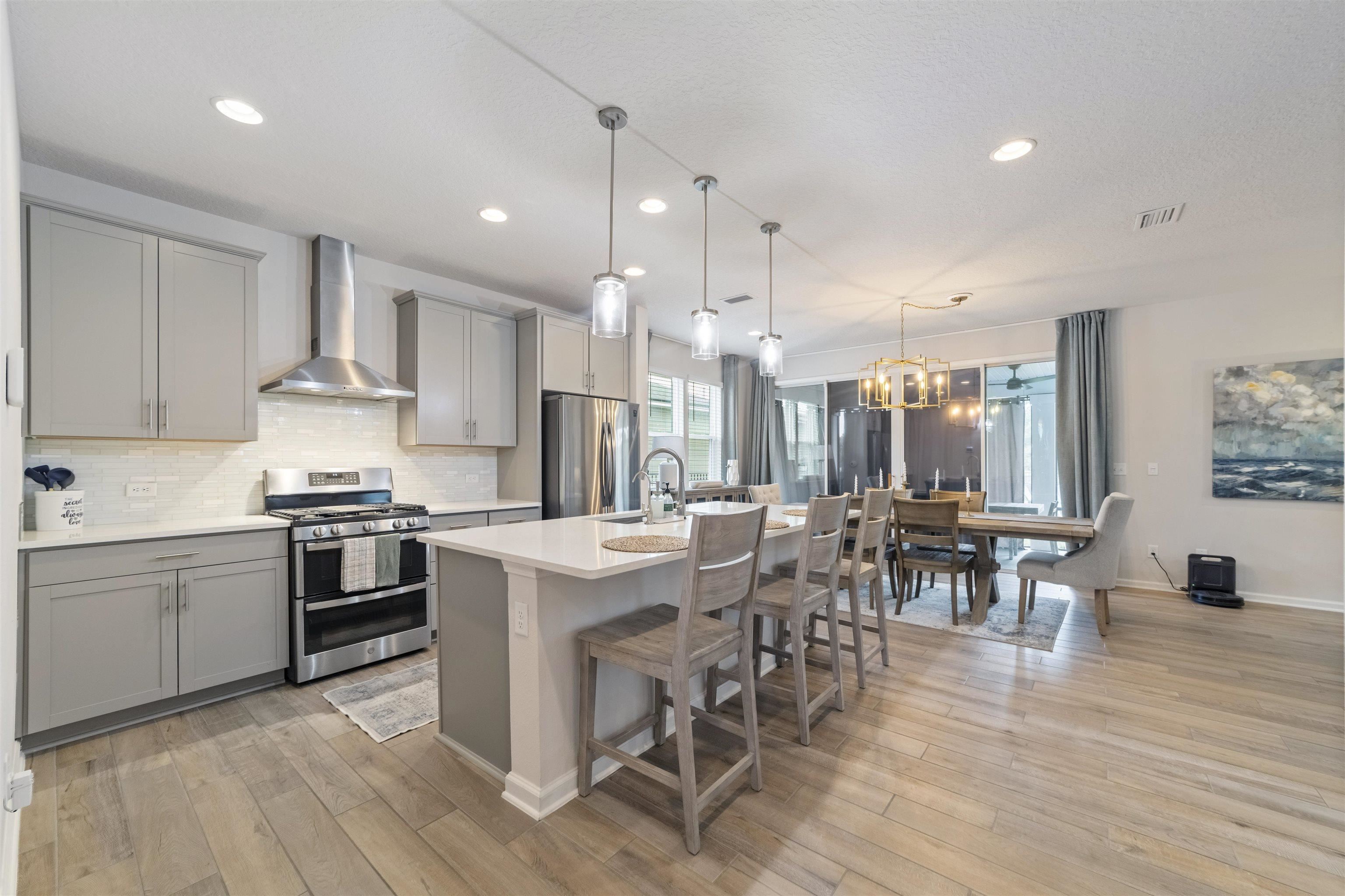 91 Pepperpike Way Street St. Augustine, FL 32092 - Photo 14 of 79 a kitchen with stainless steel appliances granite countertop a stove top oven a refrigerator a dining table and chairs with wooden floor