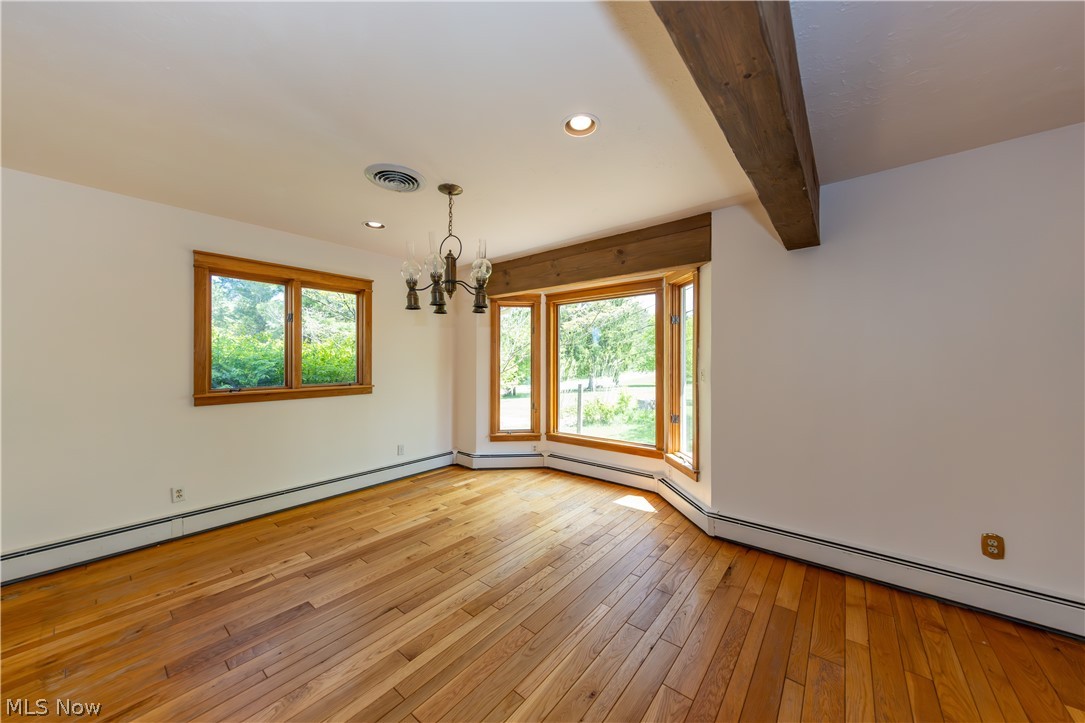 7969 Dines Road Novelty, OH 44072 - Photo 14 of 48 Spacious dining area featuring hardwood flooring, a multi-paned bay window, a standard window, a chandelier, and an exposed ceiling beam