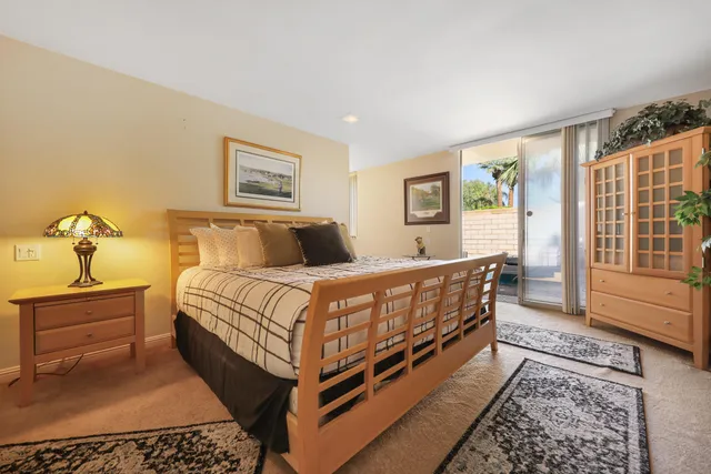 a bedroom with a bed painting on wall and a large window