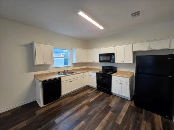 a kitchen with granite countertop a refrigerator stove top oven and sink