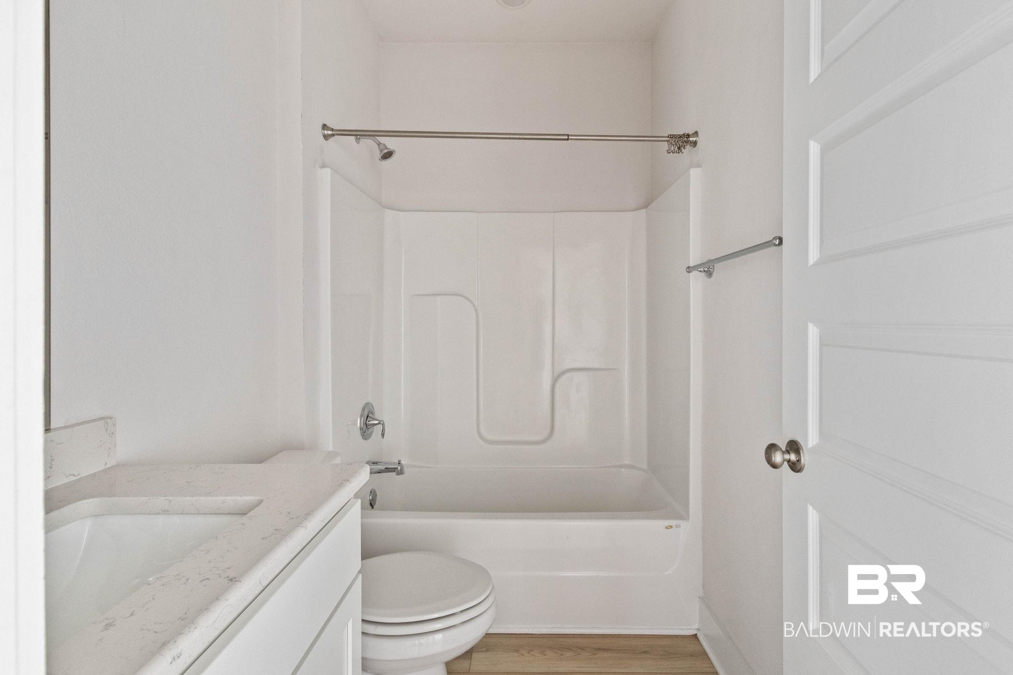 1710 Grouse Street Foley, AL 36535 - Photo 56 of 76 Bathroom featuring a white integrated tub and shower unit, a vanity with a light-toned countertop and integrated sink, a white toilet, and wood-finish flooring