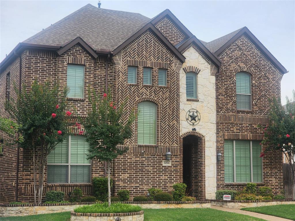 French country style house with brick siding, roof with shingles, and stone siding