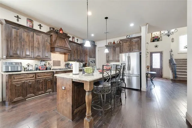 a kitchen with stainless steel appliances a dining table chairs stove and refrigerator