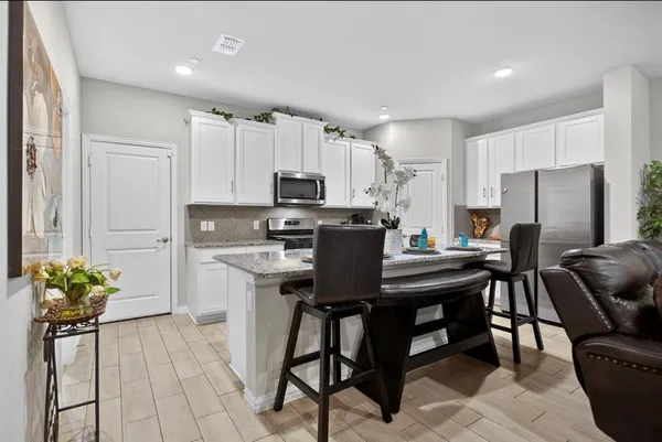 a kitchen with stainless steel appliances a table chairs refrigerator and a stove top oven