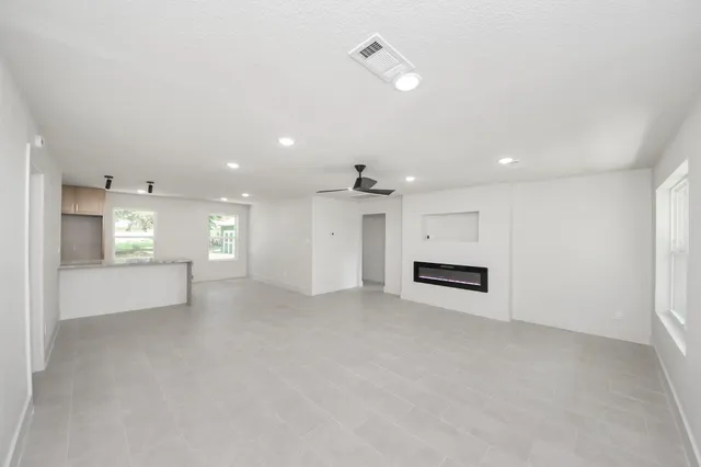 an empty room with windows and fireplace