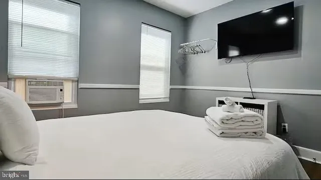 a bedroom with a bed a flat screen tv and a window