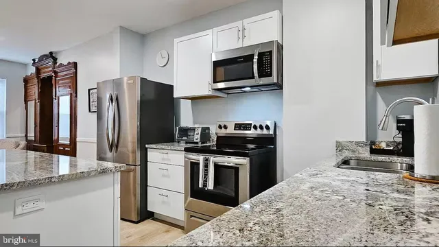 a kitchen with stainless steel appliances granite countertop a stove refrigerator and microwave