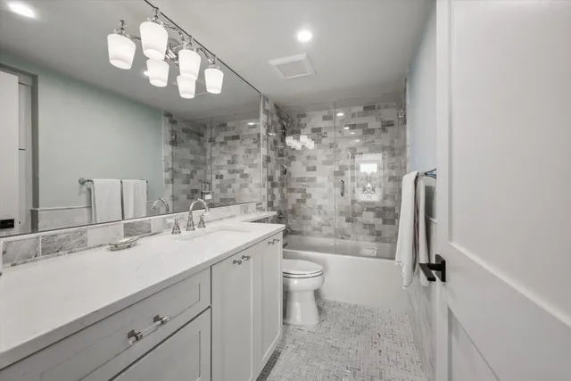 a bathroom with a sink a toilet a mirror and shower