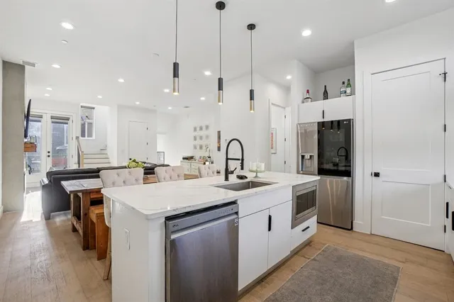a kitchen with a sink a center island stainless steel appliances and cabinets