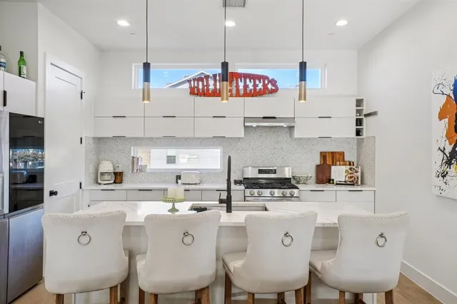 a kitchen with stainless steel appliances granite countertop a sink a stove a dining table and chairs with wooden floor