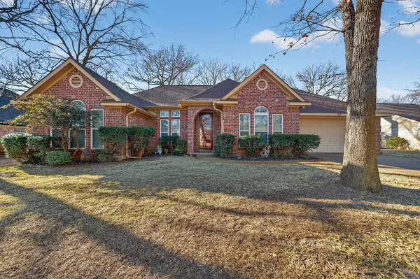 a front view of a house with a yard and large tree