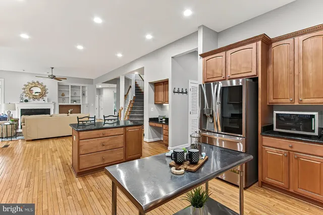 a kitchen with stainless steel appliances kitchen island granite countertop a refrigerator a stove and a wooden floors