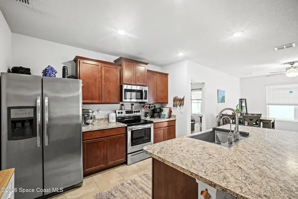 a kitchen with stainless steel appliances granite countertop a sink stove refrigerator and cabinets