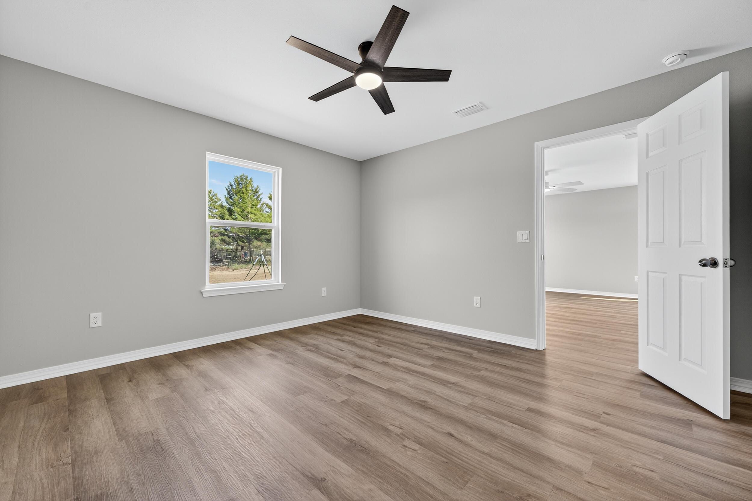 5327 B Kervin Road Crestview, FL 32539 - Photo 23 of 47 an empty room with wooden floor chandelier fan and windows