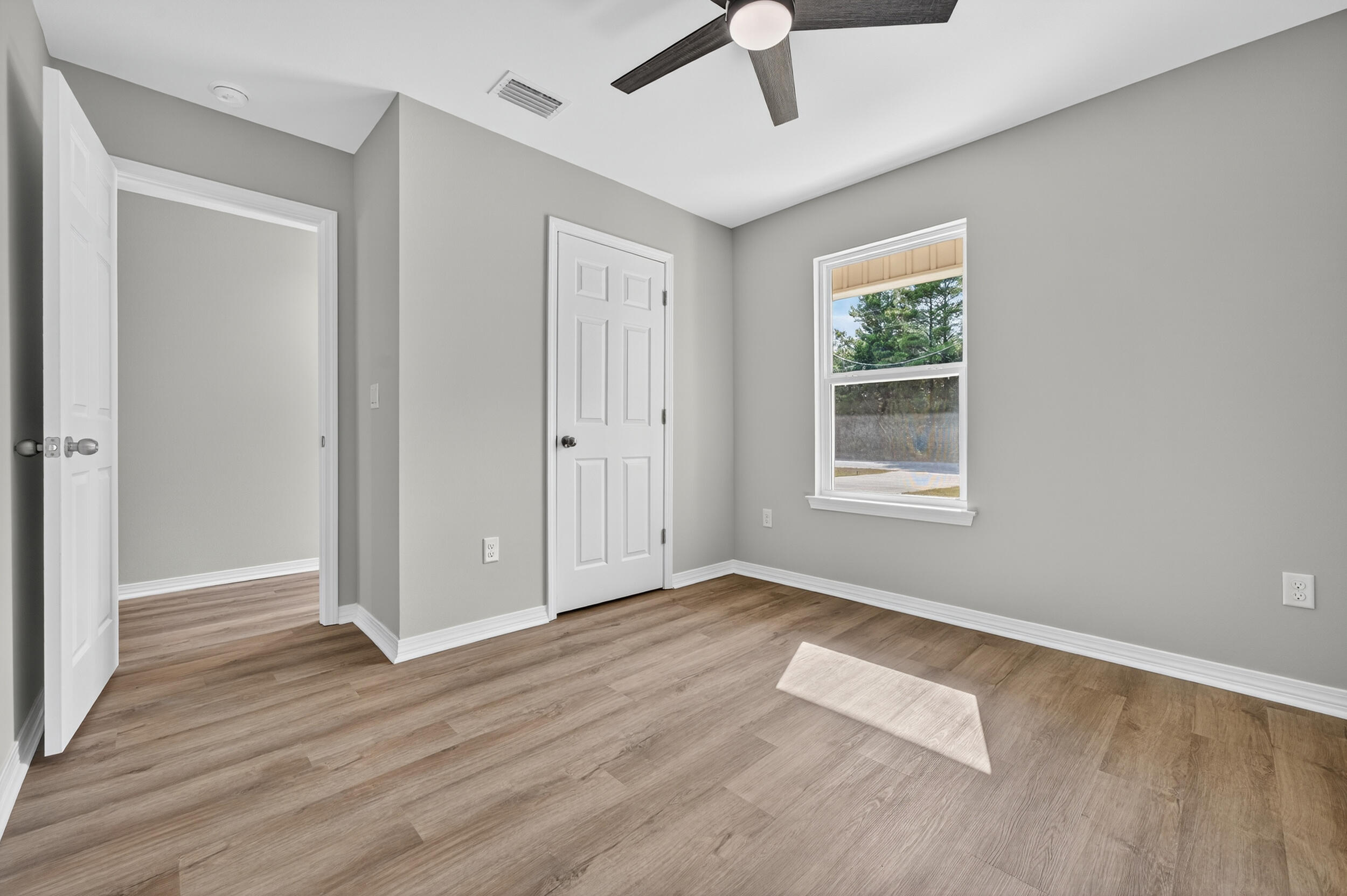 5327 B Kervin Road Crestview, FL 32539 - Photo 31 of 47 an empty room with wooden floor chandelier fan and windows
