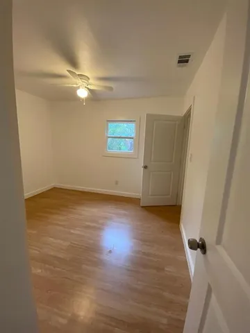 an empty room with wooden floor and ceiling fan