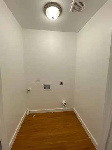 an empty room with wooden floor and natural light