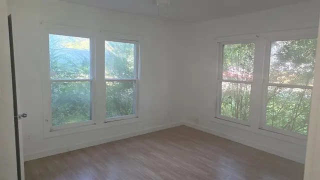 a view of an empty room with wooden floor and windows