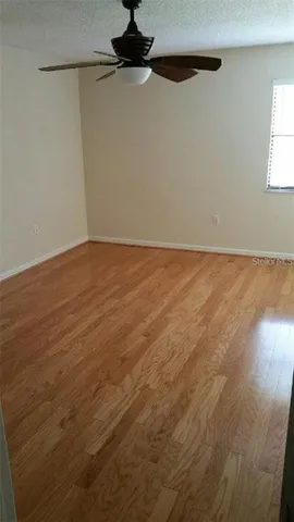 en empty room with wooden floor and fan