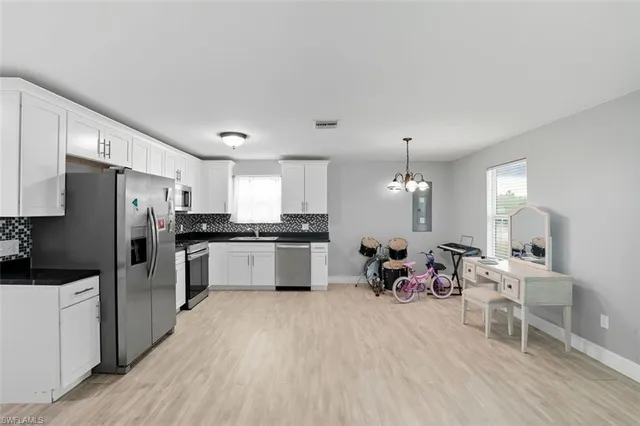 a large white kitchen with white cabinets and stainless steel appliances