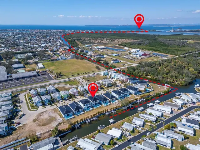 a view of a white house with a swimming pool and lawn chairs under an umbrella