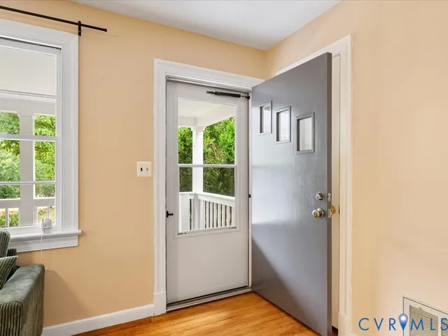 a view of a hallway with wooden floor and a bathroom