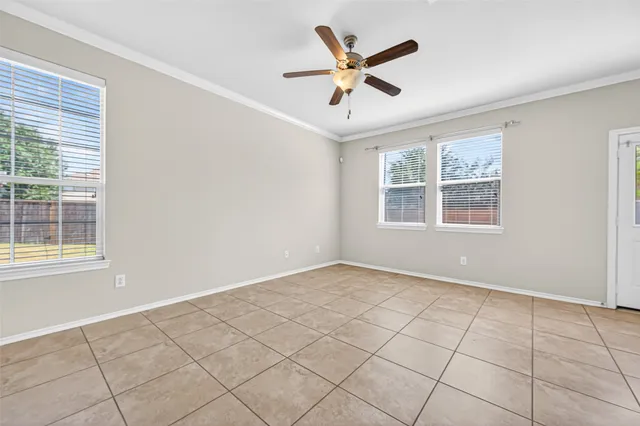 a view of an empty room with a window and ceiling fan
