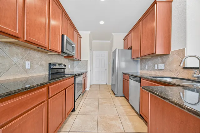 a large kitchen with stainless steel appliances granite countertop a sink a stove and a wooden cabinets