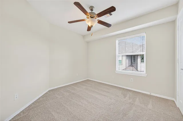 an empty room with a window and a ceiling fan