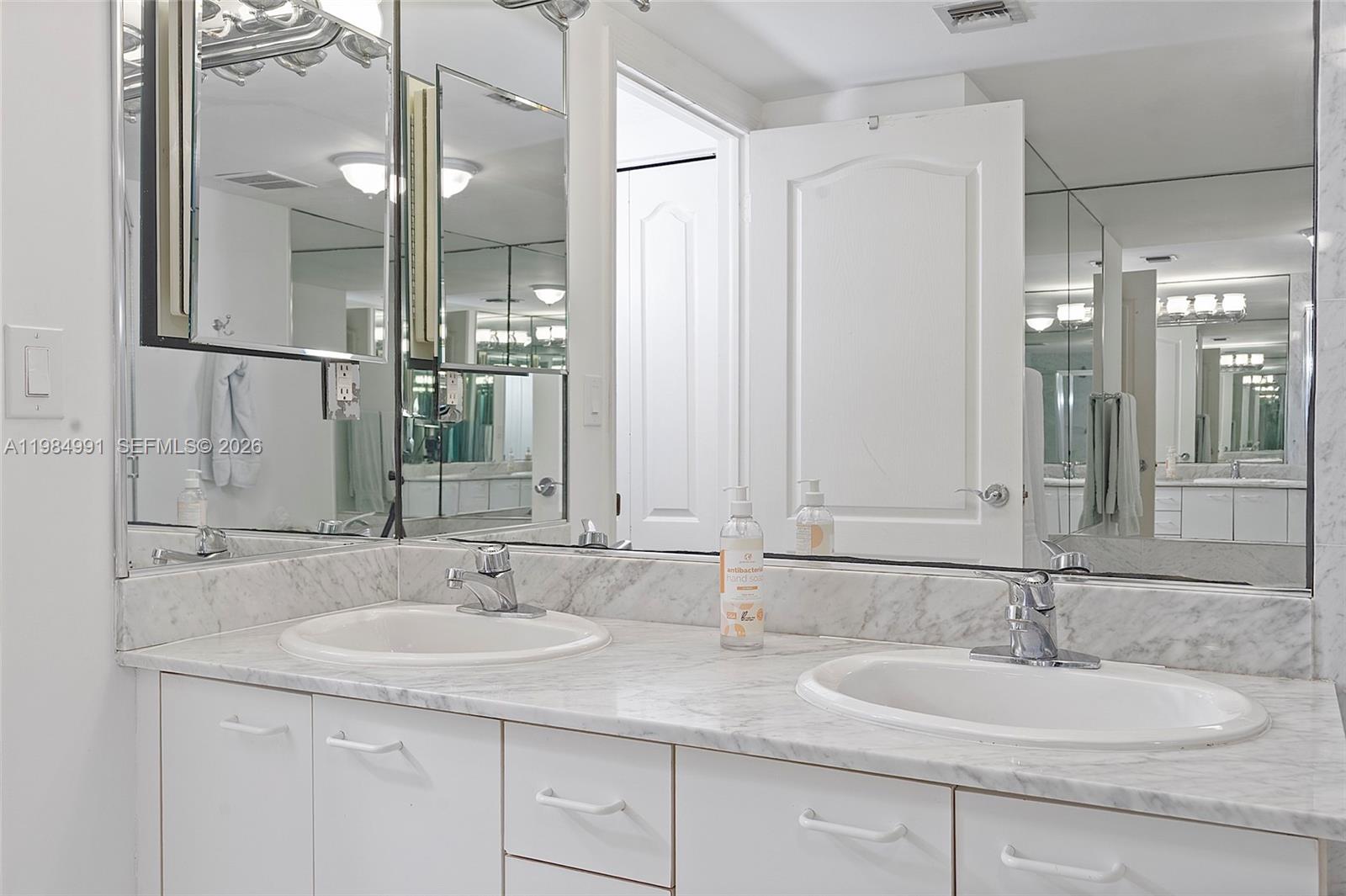 9455 Collins Avenue, Unit 409 Surfside, FL 33154 - Photo 21 of 46 a bathroom with double sink and a mirror