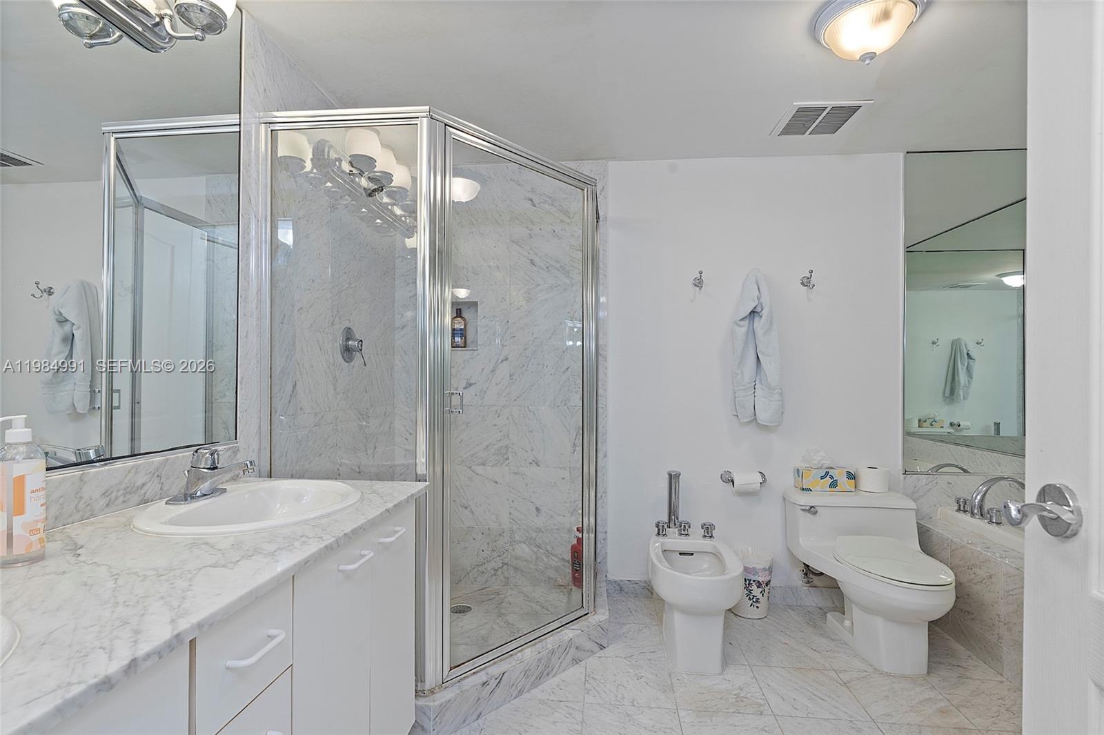 9455 Collins Avenue, Unit 409 Surfside, FL 33154 - Photo 22 of 46 a bathroom with a granite countertop shower sink mirror and toilet