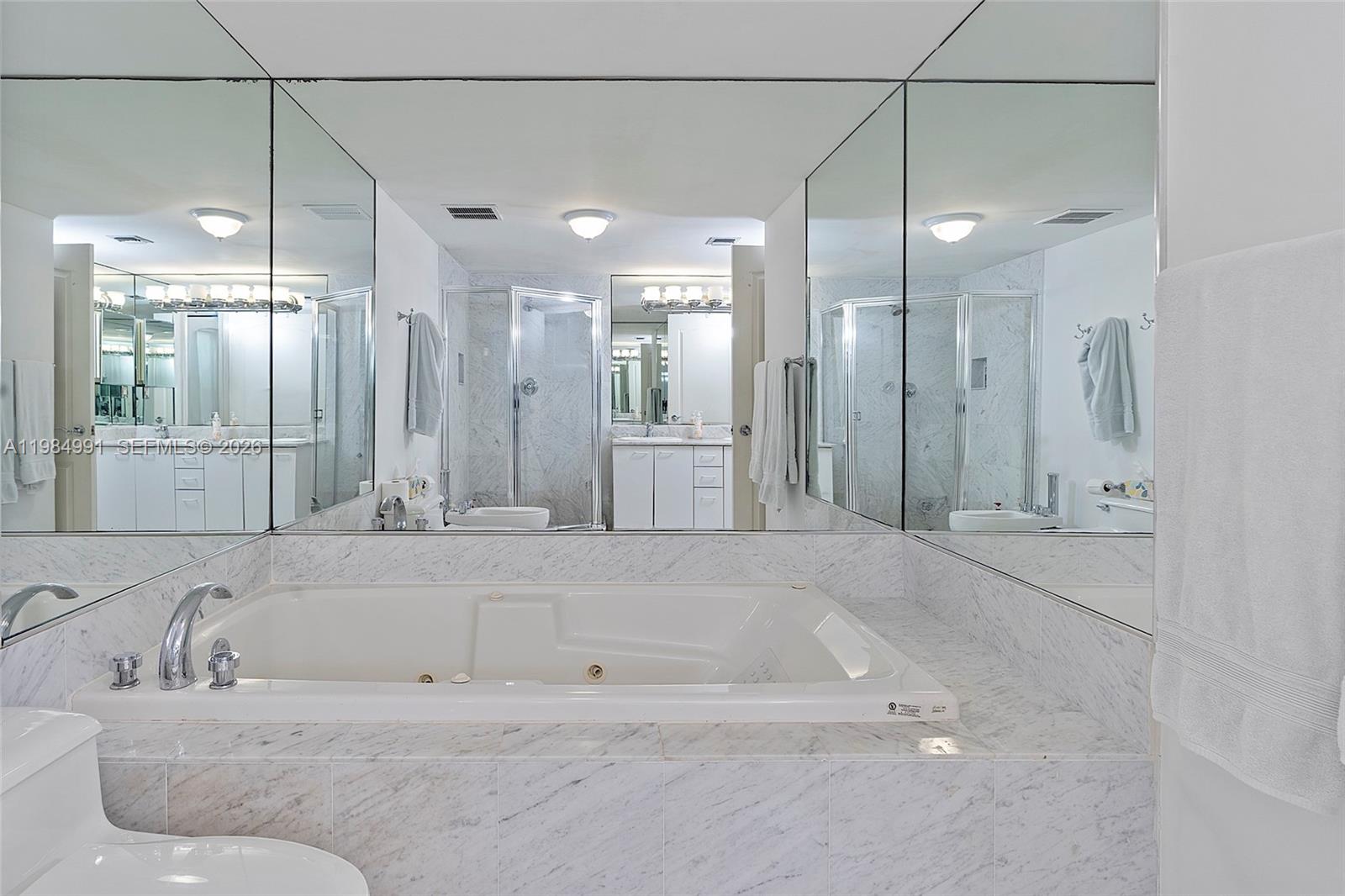 9455 Collins Avenue, Unit 409 Surfside, FL 33154 - Photo 23 of 46 a bathroom with a granite countertop sink mirror and a shower